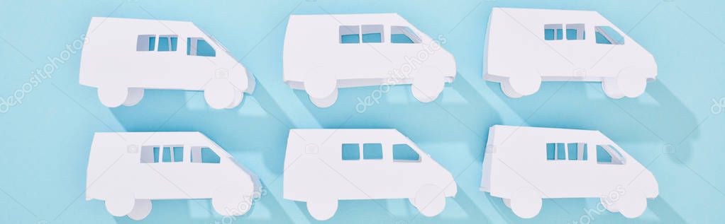 panoramic shot of white mini van models on blue background