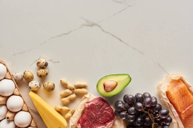 Yumurta, avokado, peynir, üzüm ve yer fıstığı ile çiğ et ve balık üst görünümü