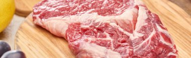 Panoramic shot of raw meat on wooden cutting board  clipart