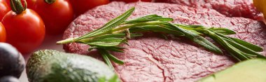 Panoramic shot of raw near steak with rosemary twig on it near cherry tomatoes clipart