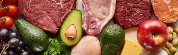 Panoramic shot of raw meat, fish and poultry near avocados, tomatoes, grape, apple cheese and peanuts