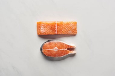 top view of raw salmon steaks on white marble surface clipart