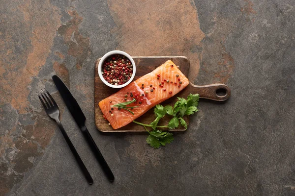 原始新鲜鲑鱼与胡椒粉的顶视图 在餐具附近的木切割板上的欧芹 — 图库照片