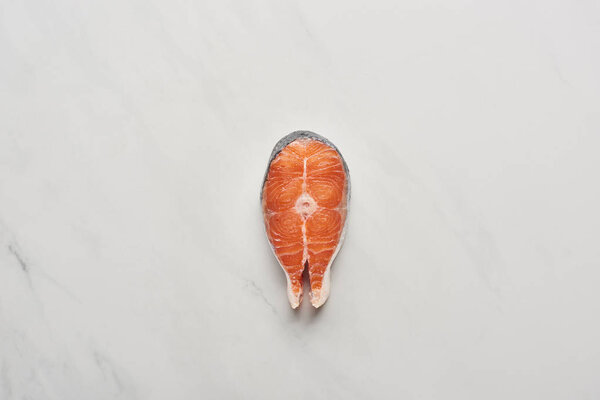 top view of raw fresh salmon steak on white marble surface