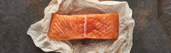 top view of uncooked salmon steak on bakery paper on stone table, panoramic shot