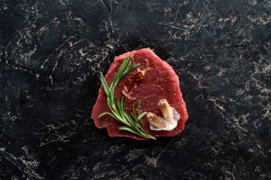 siyah mermer yüzeyinde biberiye ve sarımsak ile çiğ sığır eti üst görünümü