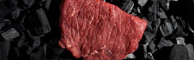 panoramic shot of raw beef sirloin on small coal pieces clipart