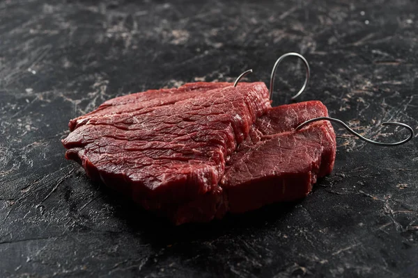 Raw Beef Steaks Metal Hooks Black Marble Surface — Stock Photo, Image