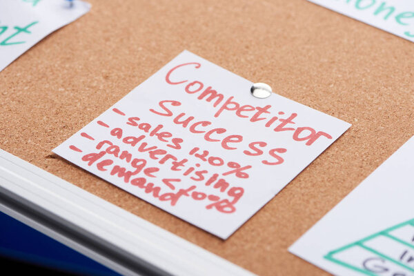 paper card with competitor success inscription pinned on cork office board