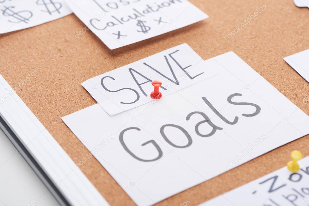 paper cards with save and goal inscriptions pinned on cork office board