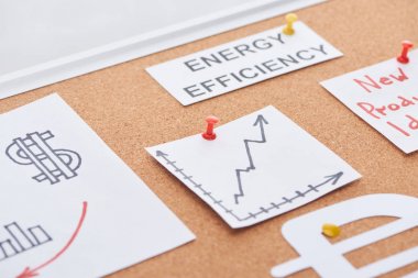 paper cards with energy efficiency text and increase chart pinned on cork office board clipart
