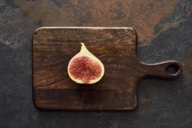 top view of ripe cut delicious fig on wooden cutting board on stone background clipart