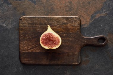 top view of ripe cut delicious fig on wooden cutting board on stone background clipart