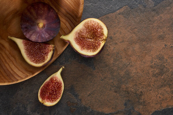 top view of ripe delicious figs on wooden board on stone background