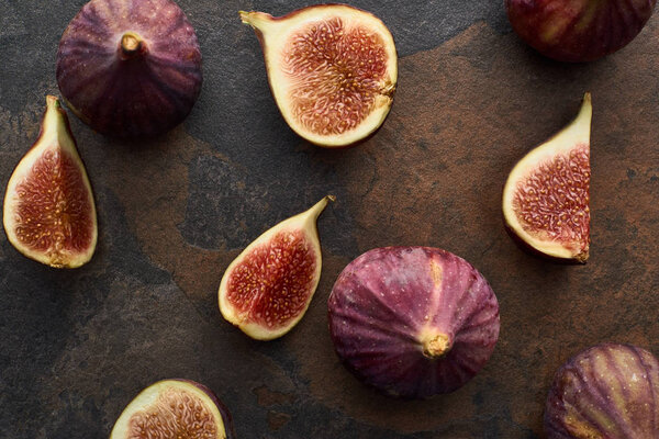 top view of ripe whole and cut delicious figs on stone background