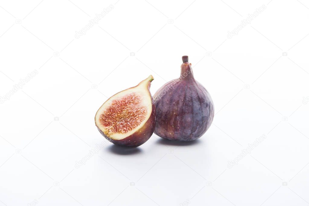 ripe whole and cut delicious figs on white background