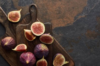 top view of ripe whole and cut delicious figs and cutting boards on stone background clipart