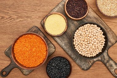 ahşap yüzeyüzerinde fasulye, kuskus, nohut, kırmızı mercimek ve Quinoa ile kase üst görünümü