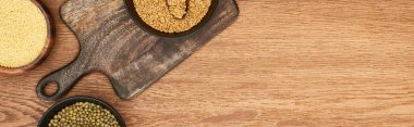 panoramic shot of bowls with couscous and beans on wooden cutting board clipart