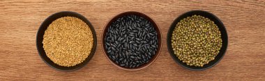 panoramic shot of bowls with diverse beans on wooden surface clipart