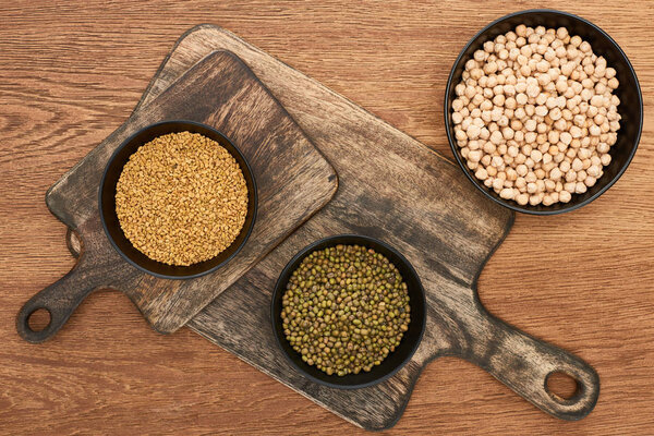 top view of bowls with chickpea and beans on wooden cutting boards