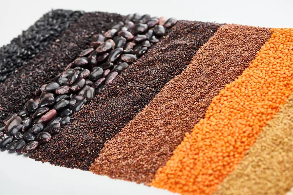 uncooked red lentil, buckwheat, quinoa, black beans and rice isolated on white