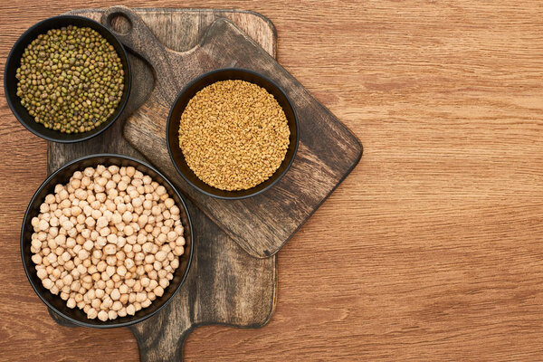 top view of bowls with moong beans and chickpea on wooden cutting boards