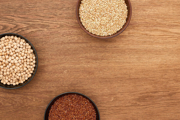 top view of bowls with quinoa and chickpea on wooden surface