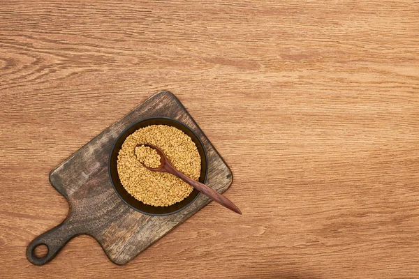 碗全谷物的顶视图与勺子在木切割板上 — 图库照片