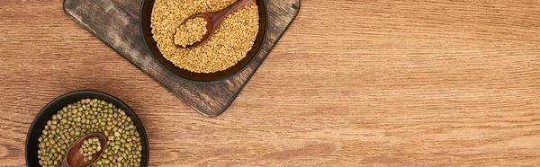 木製のまな板にスプーンと穀物とマーシ豆と黒いボウルのパノラマショット — ストック写真