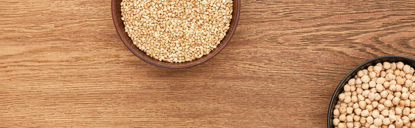 bowls with raw buckwheat and chickpea on wooden surface with copy space