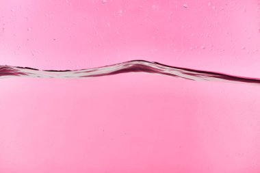 damla ile pembe arka plan üzerinde dalgalı berrak tatlı su