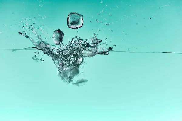 Прозрачные Кубики Льда Падающие Глубоко Чистую Воду Брызгами Бирюзовом Фоне — стоковое фото