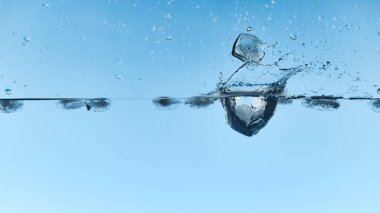 transparent water with falling ice cubes and splash on blue background clipart