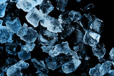 top view of frozen ice cubes with blue illumination isolated on black clipart