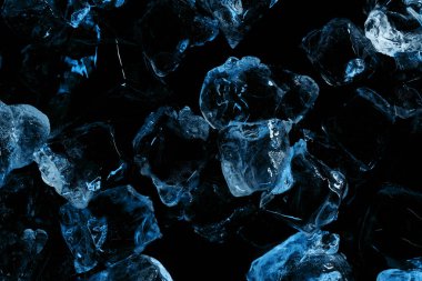 top view of frozen ice cubes with blue lighting isolated on black clipart