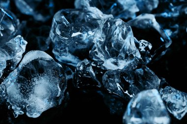 frozen ice cubes with blue lighting isolated on black clipart