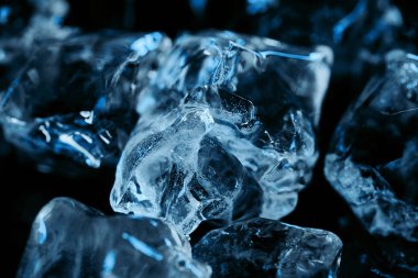 close up view of frozen ice cubes with blue lighting isolated on black clipart