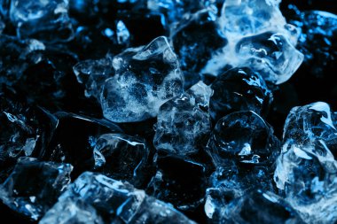 frozen clear ice cubes with blue lighting isolated on black clipart