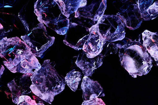 top view of transparent ice cubes with purple illumination isolated on black