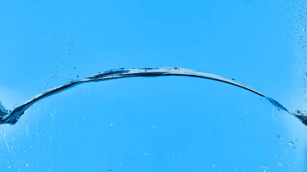 液滴が付いている青い背景の波状の透明な水 — ストック写真