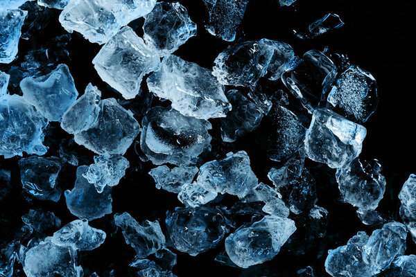 top view of frozen ice cubes with blue illumination isolated on black