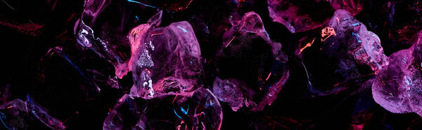 panoramic shot of transparent ice cubes with purple lighting isolated on black