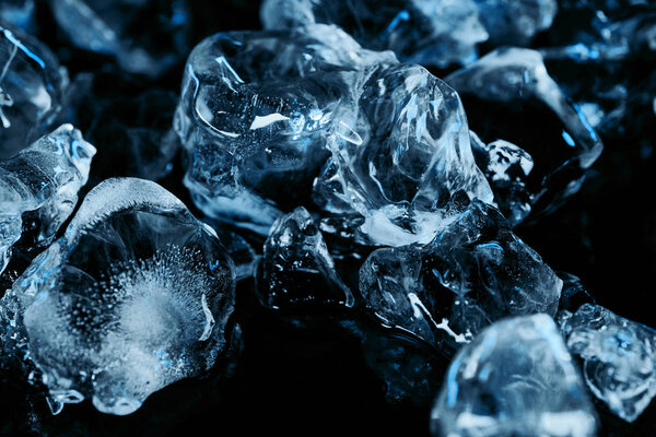 frozen ice cubes with blue lighting isolated on black