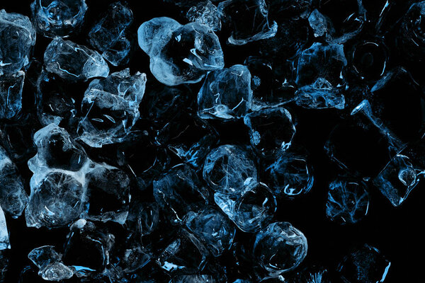 top view of frozen transparent ice cubes with blue lighting isolated on black