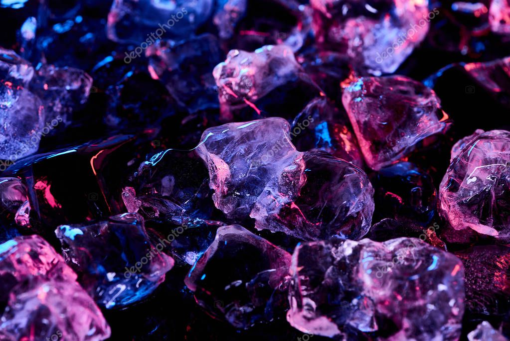 Transparent ice cubes with purple illumination isolated on black
