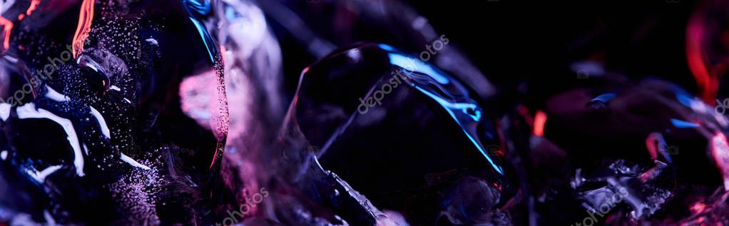 Panoramic shot of transparent ice cubes with purple colorful lighting isolated on black
