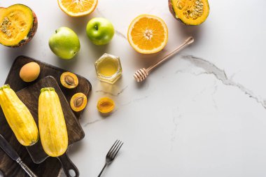 mermer yüzeyüzerinde çatal bıçak takımı ile kabak, kayısı, sarı, kabak ve bal ile ahşap kesme tahtaları üst görünümü