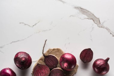 top view of beetroots and red onions on marble surface with hessian clipart