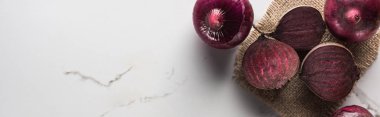 panoramic shot of beetroots and red onions on marble table with hessian clipart